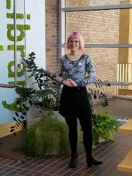 Callan Bignoli standing inside in front of potted plants with vertical sign reading