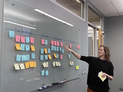 Rebecca Blakiston gesturing at wall of post-it notes
