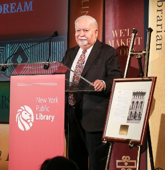 Vartan Gregorian at podium labeled with NYPL logo, elevation drawing of building on easel next to him