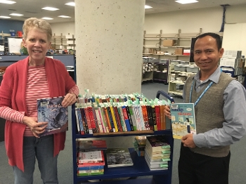 Janet Katz & Sanghak Kan on either side of library card holding Khmer-language books
