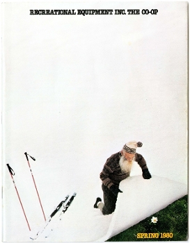 Recreational Equipment Inc. catalog showing man kneeling in snow lifting up corner of snow to reveal grass underneath and text reading