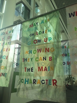 Anythink library installation, banner reading: MAY ALL CHILDREN GROW UP KNOWING THEY CAN BE THE MAIN CHARACTER