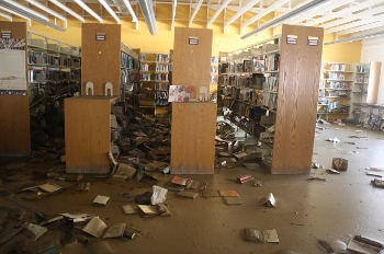 damaged library space with books falling off shelves and on floor