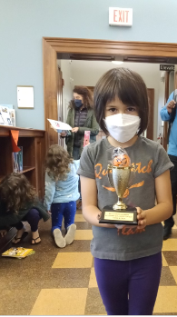 young girl wearing mask, holding trophy