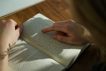 close up of hands on open book on wooden desk