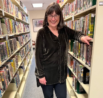 Patty Hector standing between library shelves