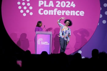 Sonia Alcantara-Antoine high fiving Mychal Threets onstage in front of PLA logo