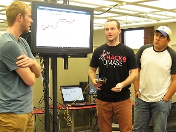 three college students presenting in front of white board in class