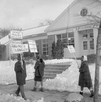 black and white photo of two women and one man picketing in front of store