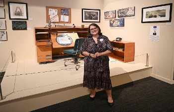 woman standing in front of display with artist's table and art on walls