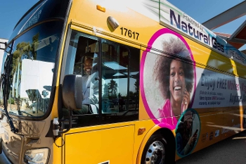 Kelvin Watson behind wheel of transit bus with library program graphics on bus exterior