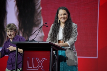 Lessa Kanani’opua Pelayo-Lozada speaking at podium with ASL interpreter