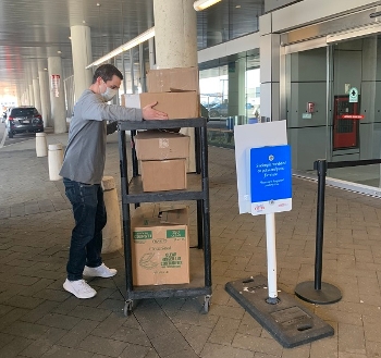 Staff unloading Books For Boston gift from Trident Books in front of a library while wearing a surgical mask due to COVID-19 outbreak