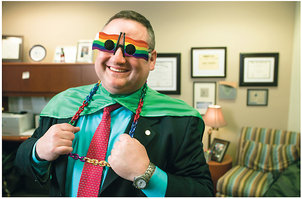 Laughing photo of Lance Werner wearing rainbow flag sunglasses, a cape, and big chain jewelry