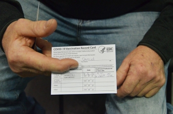 close up of man's hands holding vaccination card